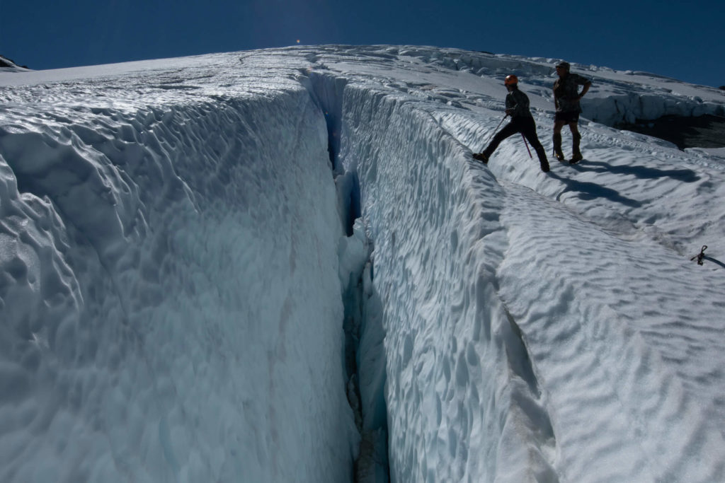 Two climbers peer in to crevasse