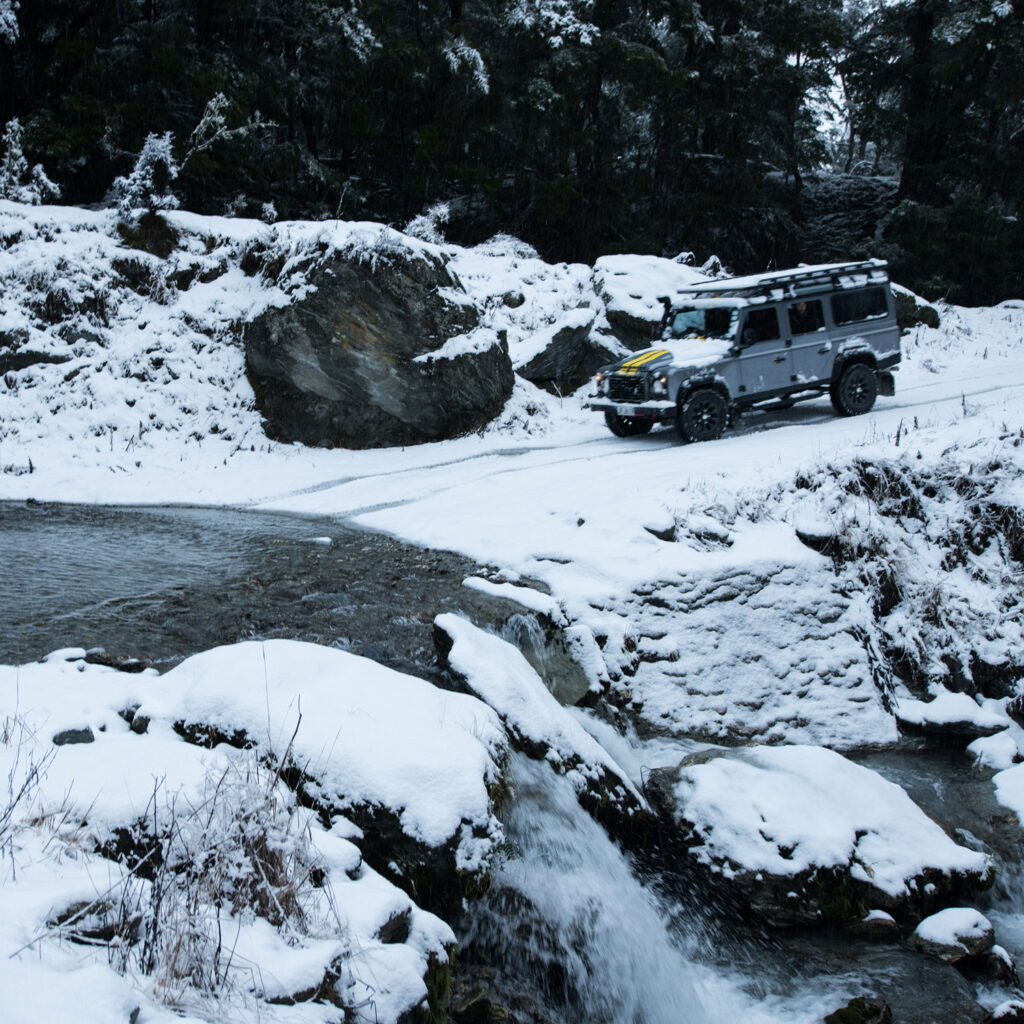 Landrover Defender 4X4 crossing a snow covered river bank